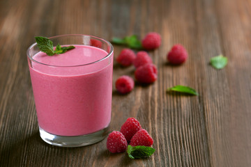 Glass of raspberry milk shake with berries on wooden background