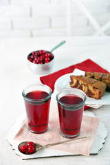 Two glasses with cherry juice on table, on light background