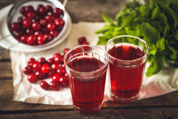 Two glasses with cherry juice on table, on wooden background