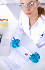 Fototapeta premium Woman researcher is surrounded by medical vials and flasks