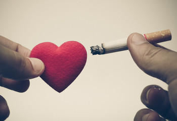 male hand pointing a cigarette into a red heart