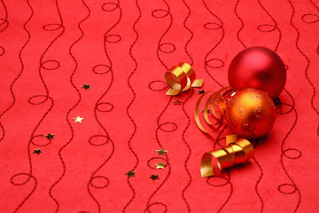 Red christmas ball with a curly ribbon on red background