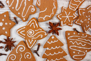 Fresh baked decorated gingerbread with spices on old wooden background, christmas time