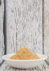 Lemongrass powder in a white bowl over wooden background