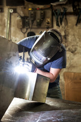 Welder welding sheet metal in a workshop - obrazy, fototapety, plakaty