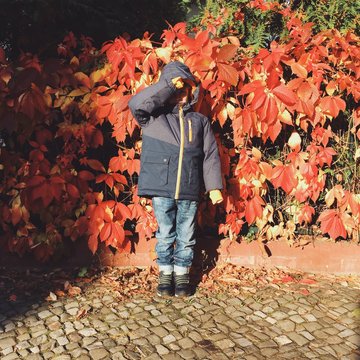 Boy protecting his eyes from bright early morning sun in autumn