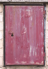 Old pink weathered door of the electricity circuit breaker. 