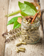 Herb capsule with green herbal leaf on wood