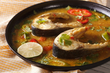 Tasty fish curry with vegetables close-up on a plate. Horizontal
