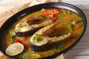 Spicy fish curry with vegetables close-up on a plate. horizontal
