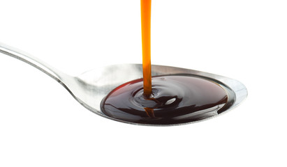 Pouring Soy Sauce on spoon isolated on white,Selective focus