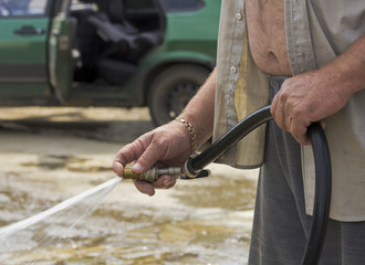  Two male hands holding a hose with water spurting out.