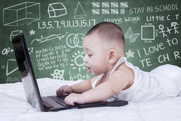 Attractive baby using laptop with scribble background