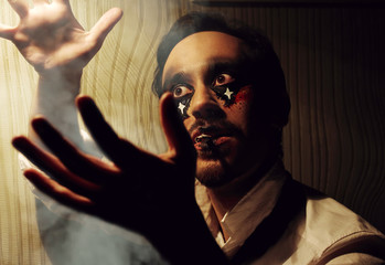 Young stylish man with art hallowen party grimm. Smoke magic.