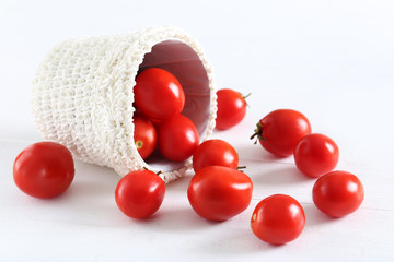 Fresh red tomatoes in basket on white wooden background
