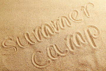 Summer camp handwritten in a beach sand