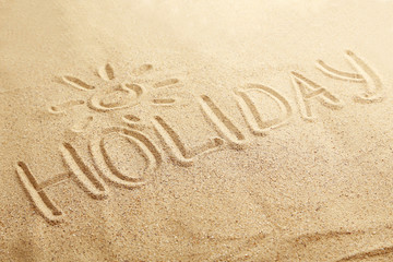 Naklejka na ściany i meble Holiday handwritten in a beach sand