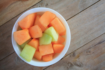 melon slices in white dish on wood table