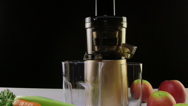  New masticating juicer machine with fresh fruit and vegetables on black background