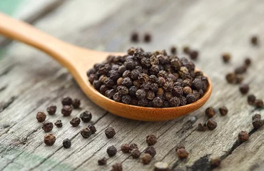 Poster Whole black pepper on wooden spoon © sommai
