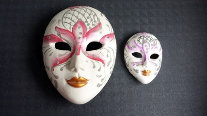 Two Venetian masks with plaster on dark background