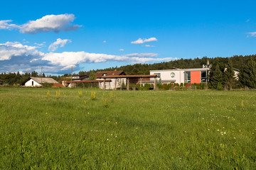Modern house and old hayrack in the village near the field.