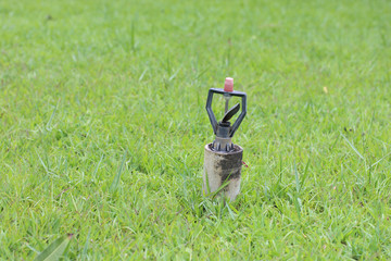 Automatic water sprinkler on green grass.