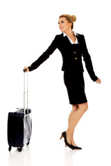 Fototapeta premium Smile businesswoman dragging wheeled suitcase