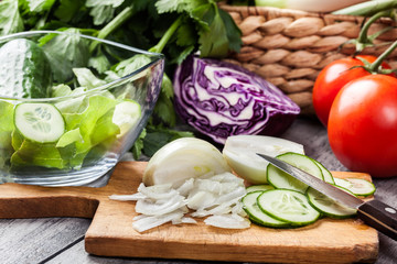 Chopped vegetables: onion and cucumber on cutting board