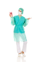Female surgeon doctor holding piggy bank