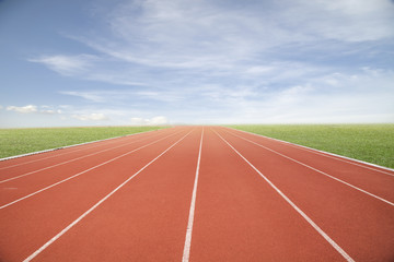 Running track with green grass and blue sky white cloud.