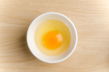 Fresh egg yolk in the bowl on wooden background,food ingredient - obrazy, fototapety, plakaty