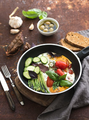 Pan of fried eggs, salami, asparagus, cherry-tomatoes with bread