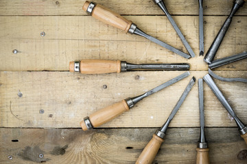 Set of chisels arranged in circle over wooden background 