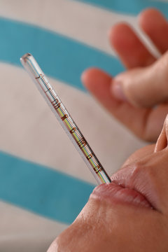 Detalle de boca con termometro midiendo fiebre.enferma.