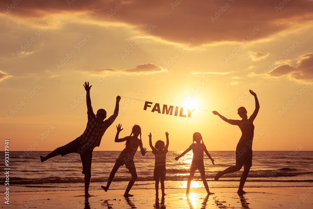 Poster happy family standing on the beach at the sunset time.