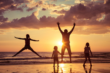 Father and children playing on the beach at the sunset time.