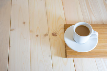 Coffee cup in the morning sunshine on wood floor.