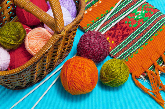 Basket with balls of wool and knitting needles on a blue background