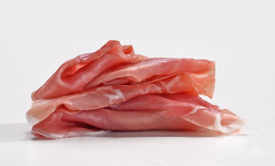 Rebanadas de jamon serrano crudo en fondo blanco.