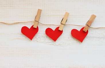 Garland of paper hearts pinned on twine - wall hanging love paper decoration banner for Valentine's Day, empty wooden surface