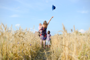 A mother and two kids walking away across a field of wheat