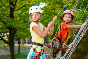 Fototapeta na wymiar Cute children. Boy and girl climbing in a rope playground