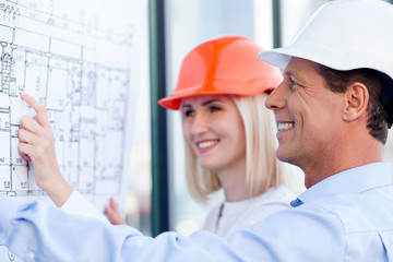 Cheerful engineers are discussing plan of building
