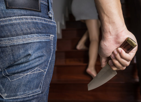 Criminal with Knife attack woman in a house,focus hand , in dark