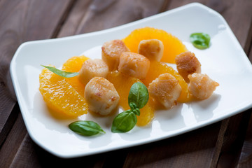 Roasted sea scallops with orange filet on a glass plate