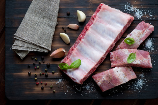 Raw pork ribs with seasonings on a rustic wooden surface