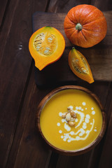 Pumpkin cream-soup on a dark rustic wooden surface, top view