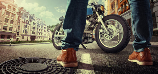Еravel. Biker standing near the motorcycle on the street at sunny day. Close view on legs
