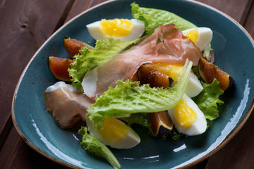 Salad with fresh fig fruits, ham and eggs. Close-up, top view